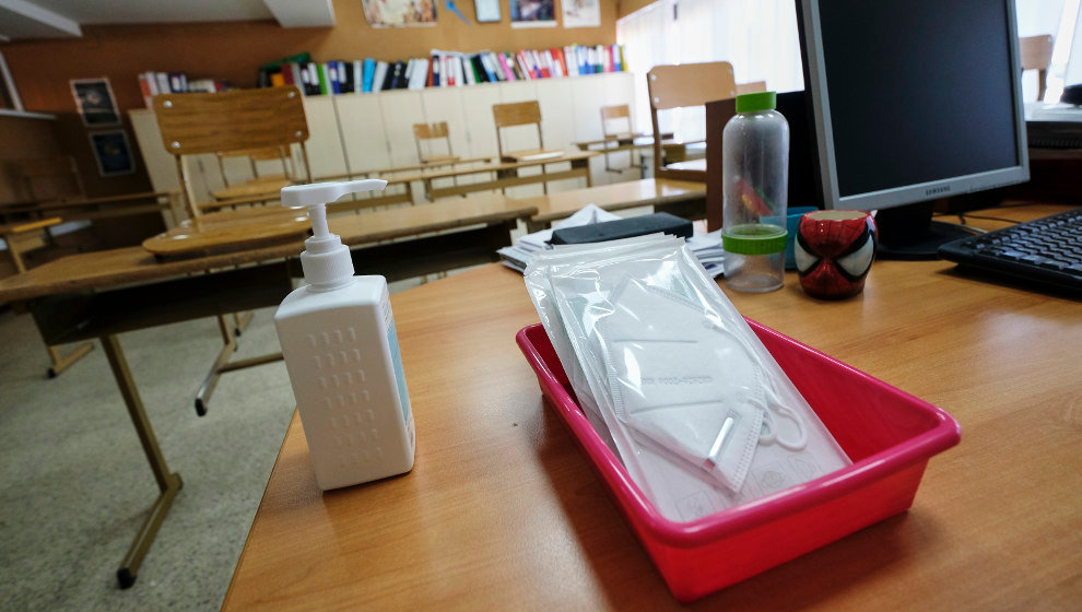 Mascarillas y gel desinfectante en la mesa del profesor de un aula