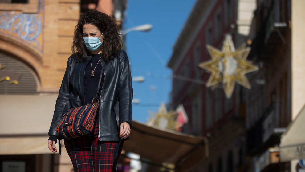 Una mujer con mascarilla camina por la plaza de San Francisco, en Sevilla