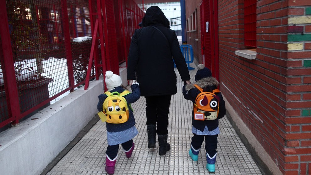 Un familiar lleva de la mano a dos alumnos del colegio