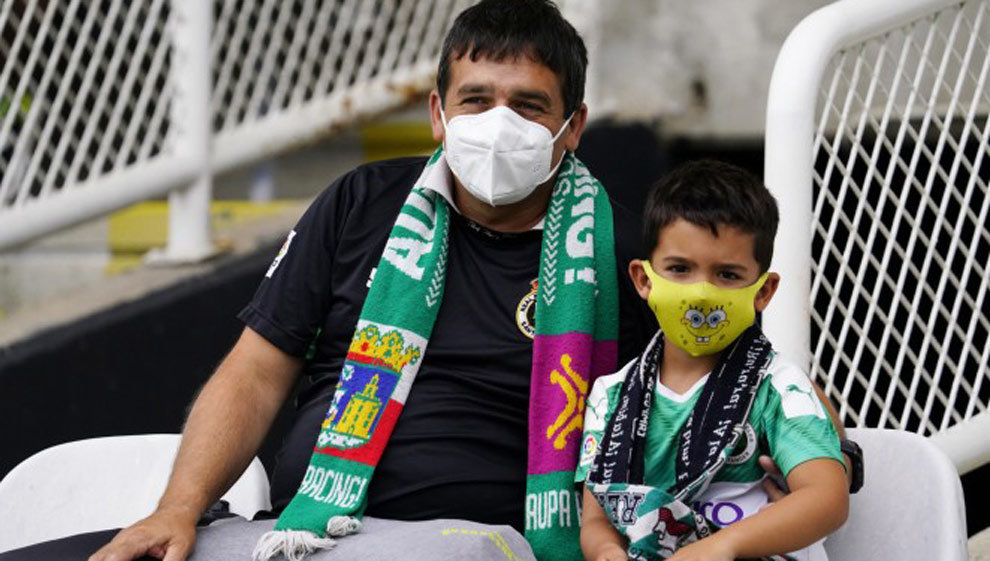 Un padre y su hijo sentados en las gradas mientras siguen un entrenamiento