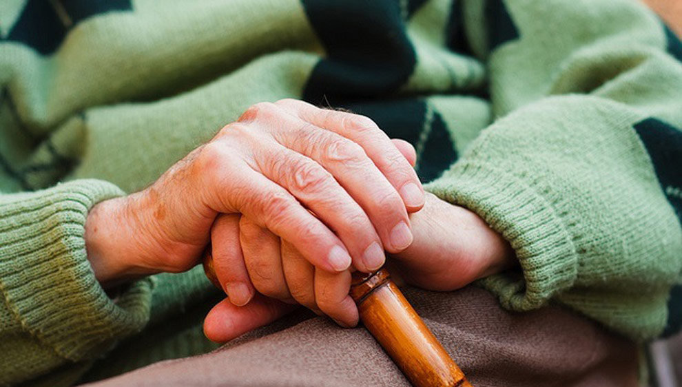 Un anciano descansa en una silla con su bastón