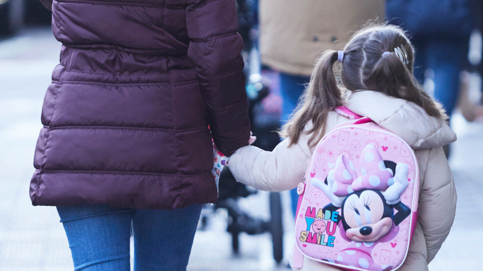 Una niña, acompañada de un madre, durante la vuelta al cole