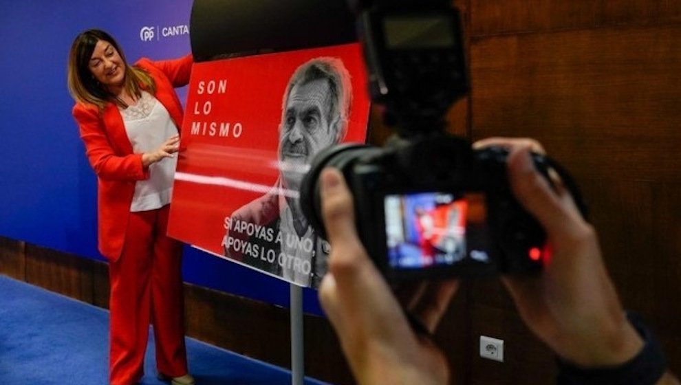 La presidenta del PP de Cantabria, María José Sáenz de Buruaga, mostrando el cartel con las caras de Revilla y Sánchez