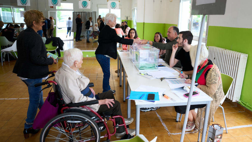 Varias personas ejercen su derecho al voto en el colegio electoral