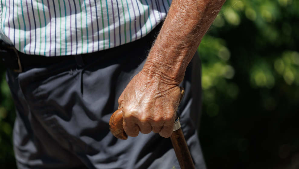 Un hombre mayor pasea apoyándose en un bastón