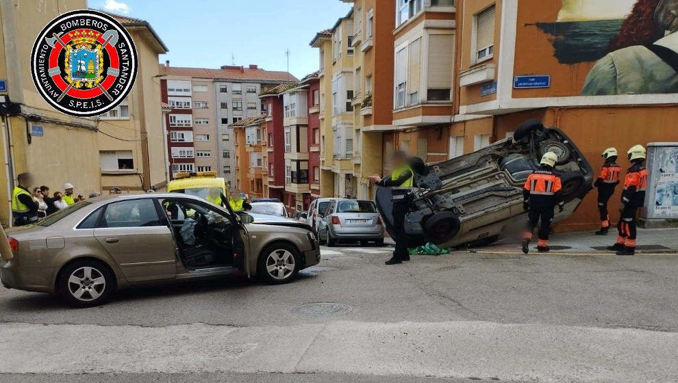 Los bomberos ponen sobre sus ruedas a un coche que quedó de costado tras chocar contra otro