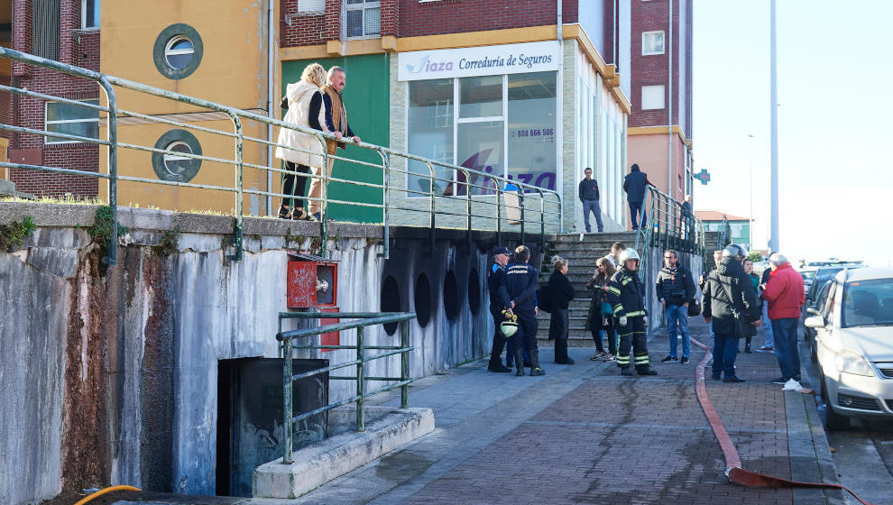 Bomberos y vecinos en las inmediaciones del incendio de un garaje comunitario en la calle José María Cossío