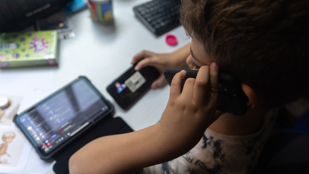 Un niño usa el teléfono móvil y una tablet