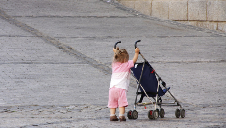 Una niña empuja una silla de bebé