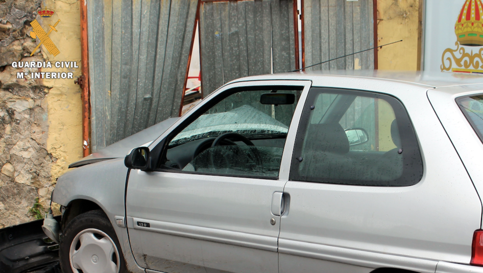 El coche siniestrado contra la puerta metálica de un inmueble de Helguera en Reocín