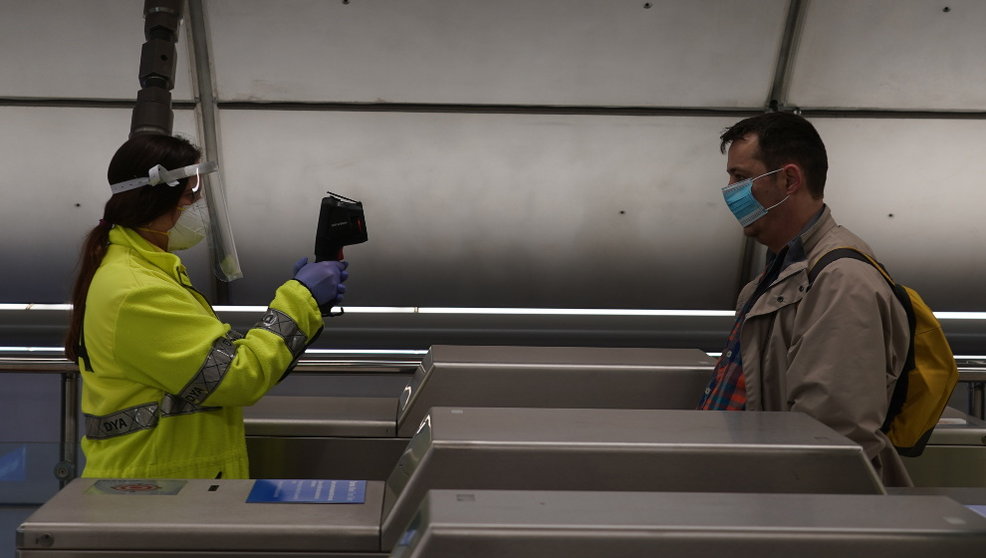 Una voluntaria de la DYA toma la temperatura con una pistola a un viajero en la estación de metro de Otxarkoaga