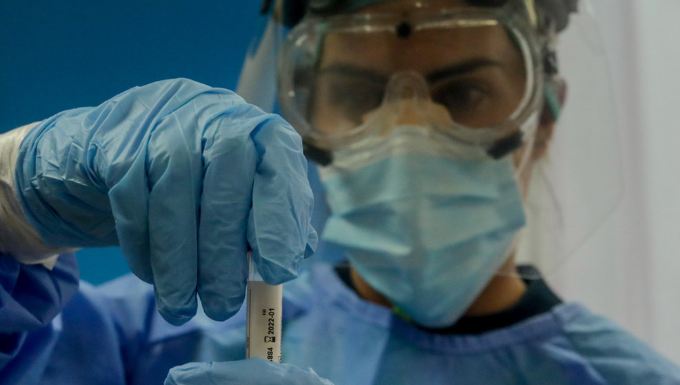 Una trabajadora sanitaria sostiene una probeta con una prueba PCR
