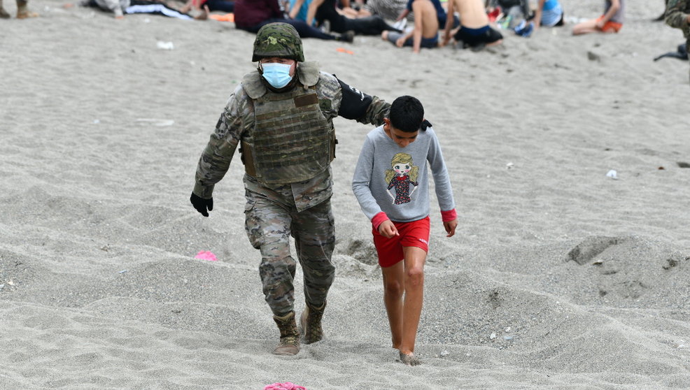 Un militar del ejército español acompaña a un niño en una jornada marcada por las devoluciones en caliente que están efectuando a los migrantes que han entrado en Ceuta procedente de Marruecos, a 18 de mayo de 2021, en Ceuta, 