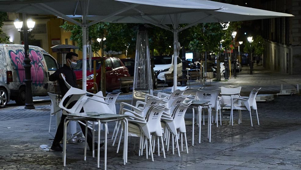 Una persona recoge la terraza de una cafetería