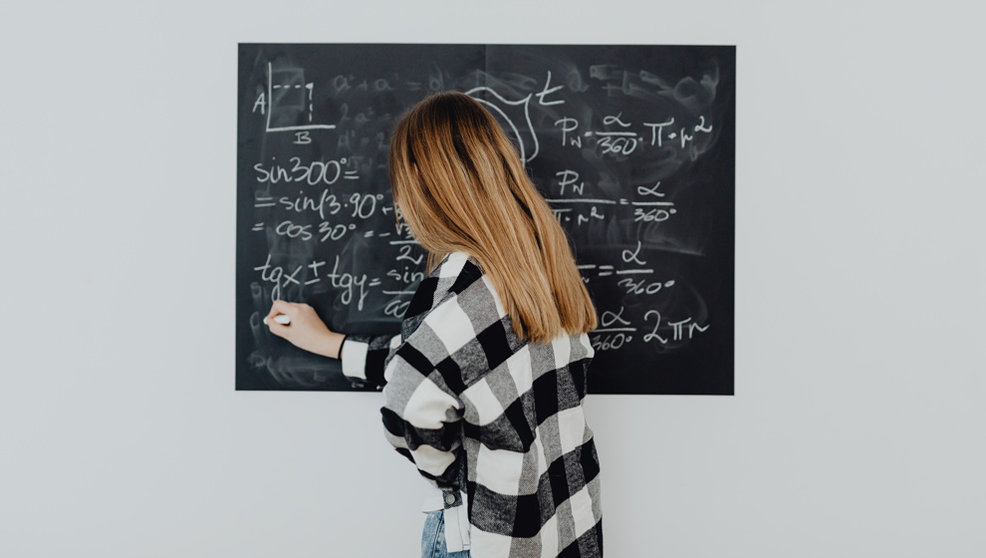 Una mujer escribe en una pizarra un problema de matemáticas