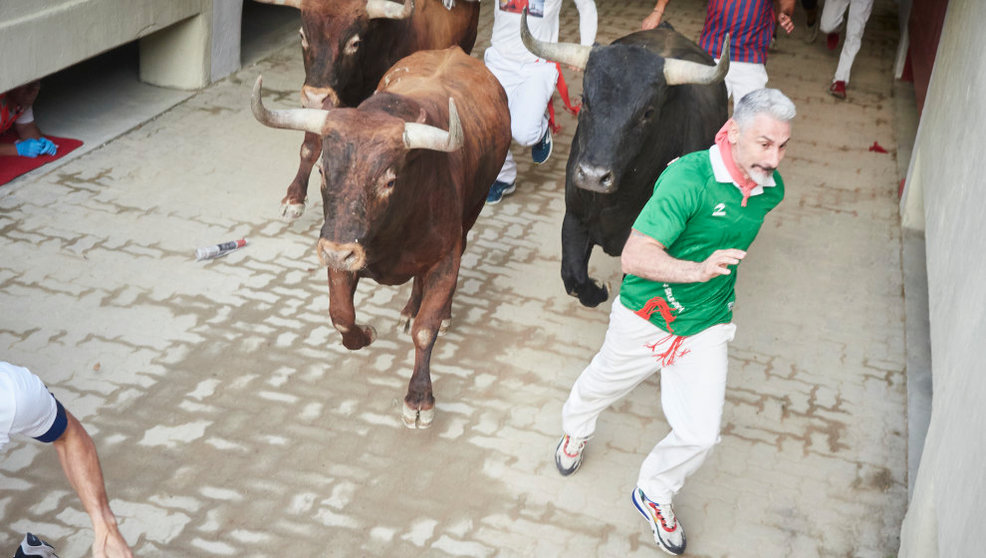 Un hombre corre durante el último encierro de las Fiestas de San Fermín 2022 con toros de Miura