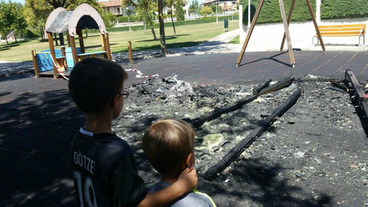 Dos niños contemplan el parque infantil de Zizur Mayor calcinado tras un acto de vandalismo