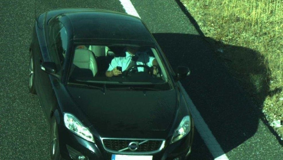 Conductor mirando su móvil mientras conduce y captado por una cámara de la DGT