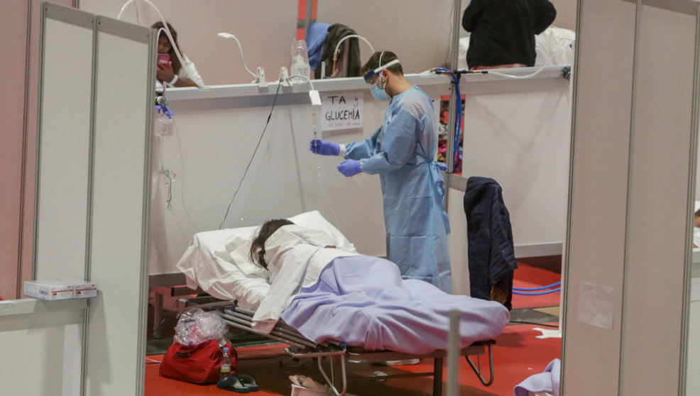 Un sanitario protegido con mascarilla atiende a una paciente ingresada por coronavirus en IFEMA