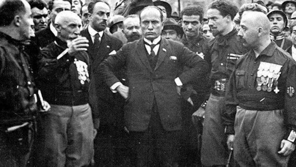Benito Mussolini, en el centro de la imagen, mira desafiante al vacío en un encuentro de los “camisas negras” del fascismo.