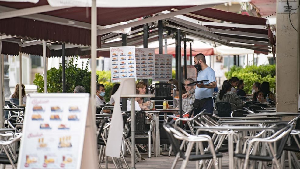 Un camarero atiende una mesa en la terraza de una cafetería