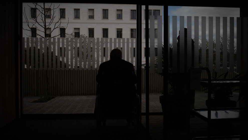 Un hombre en silla de ruedas observa el exterior de una residencia
