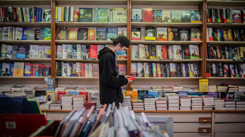 Un joven observa un libro en una librería