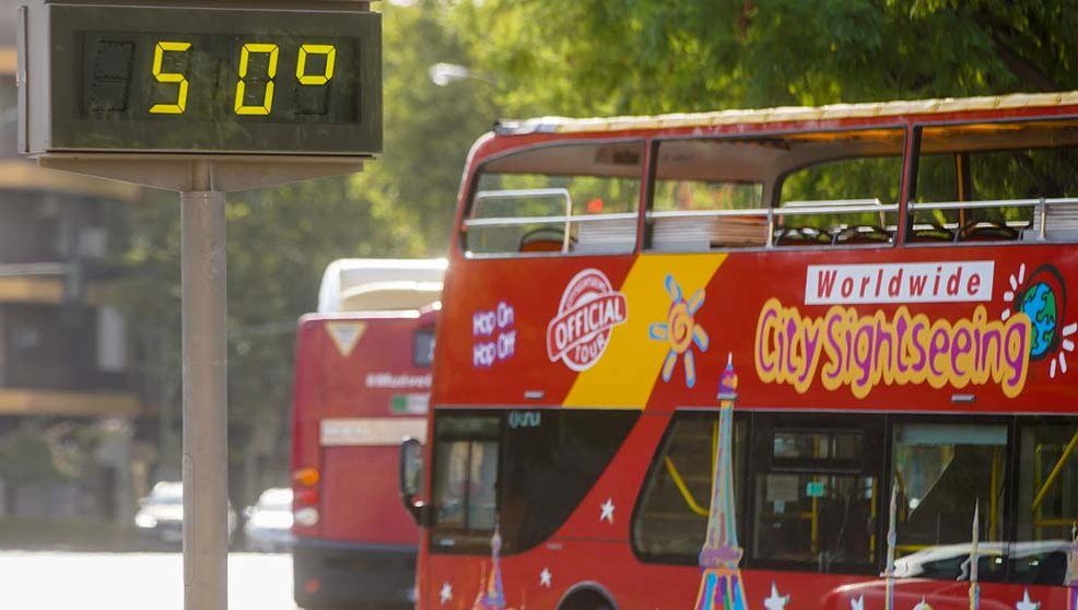 Un autobús turístico pasa sin pasajeros delante de un termómetro que marca 5Oº en otro día con altas temperaturas en Sevilla