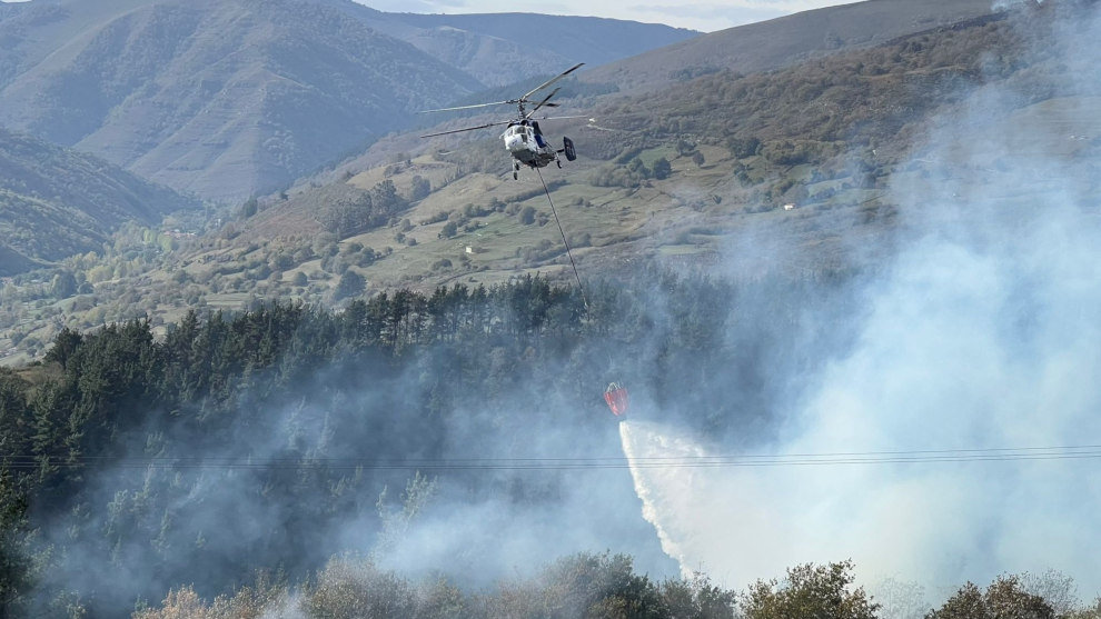 Un helicóptero trata de apagar el incendio forestal en Arenas de Iguña