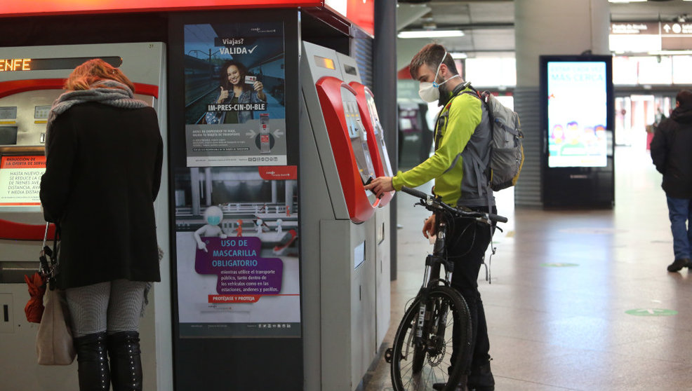 Un viajero con bicicleta adquiere un billete en un dispensador en la estación de Atocha