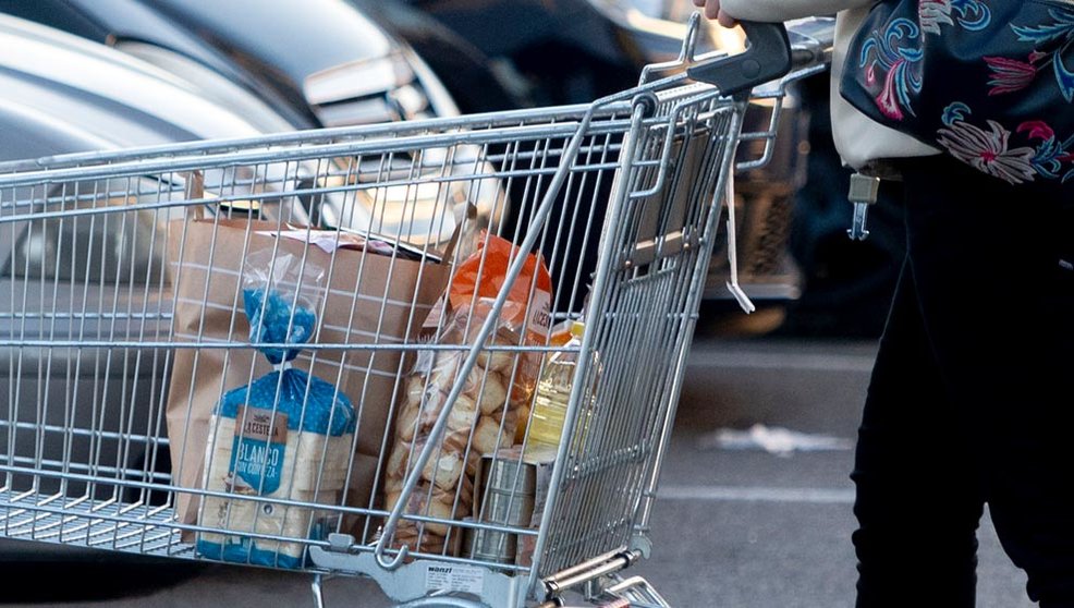 Una mujer sale de un supermercado con un carro de la compra