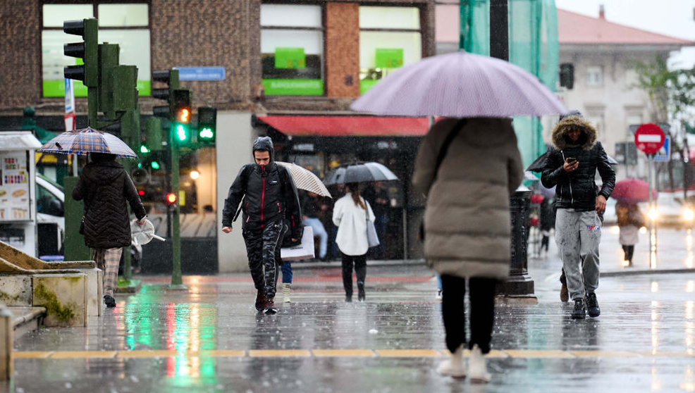 Varias personas con paraguas cruzan un paso de cebra, a 16 de enero de 2023, en Santander