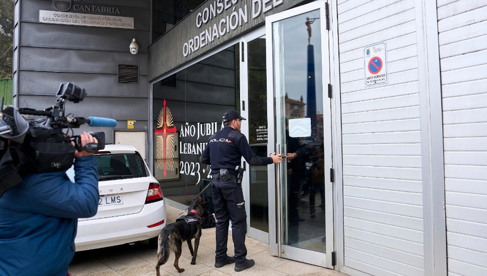Un agente de la Policía Nacional entra con un perro a las dependencias de la Consejería de Obras Públicas