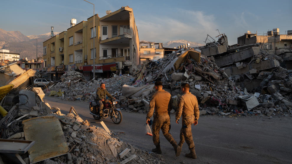 Varias personas caminan por los escombros de los edificios derribados por el terremoto de Turquía