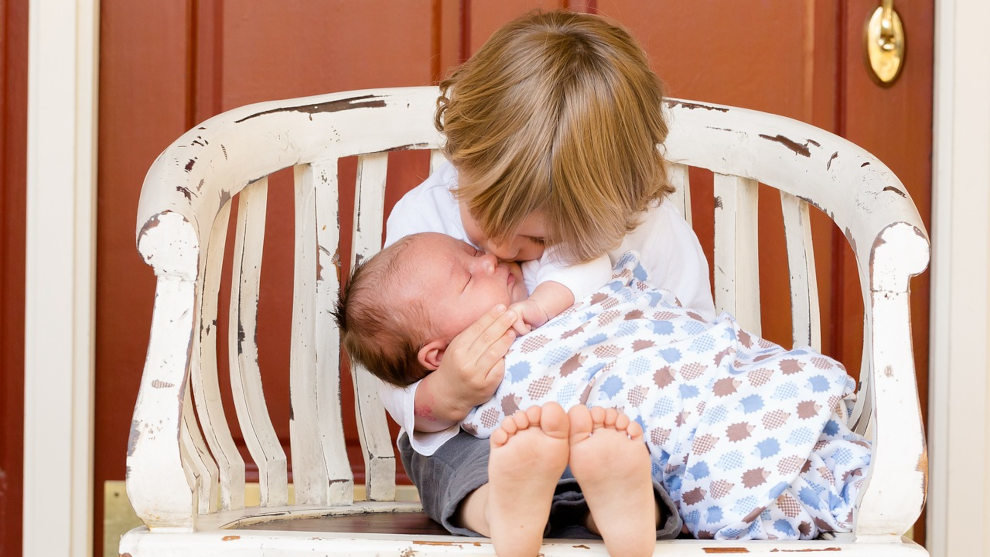 Un niño pequeño besa a un bebé