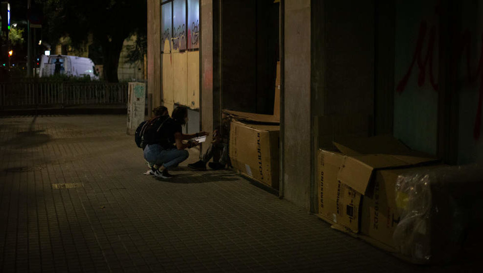 Una voluntaria habla con personas que duermen en cajas de cartón