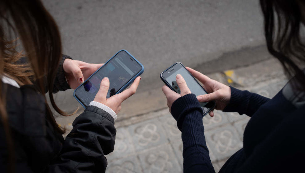 Dos jóvenes utilizando su teléfono móvil
